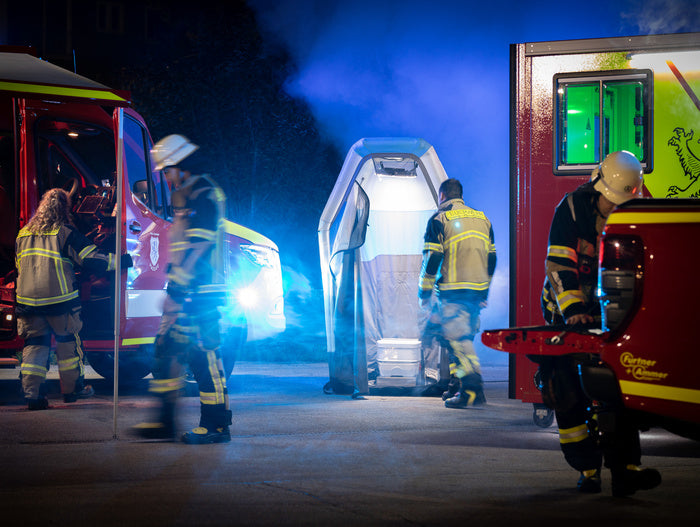 Einsatzstelle bei Nacht: Einsatzkräfte zwischen zwei Fahrzeugen, dazwischen eine aufgestellte, beleuchtete Kabine