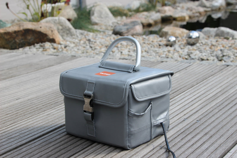 Vlitex Battery Safety Box L on a patio, with the charging cable running out of the closed box