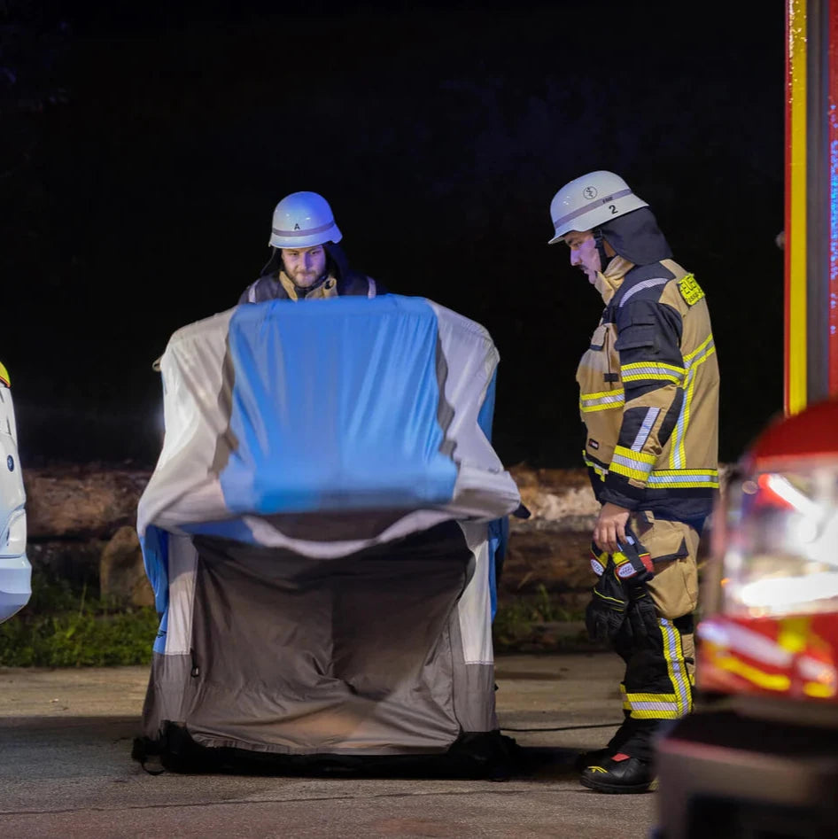 Zwei Einsatzkräfte bauen das aufblasbare Hygienezelt bei Nacht an der Einsatzstelle auf