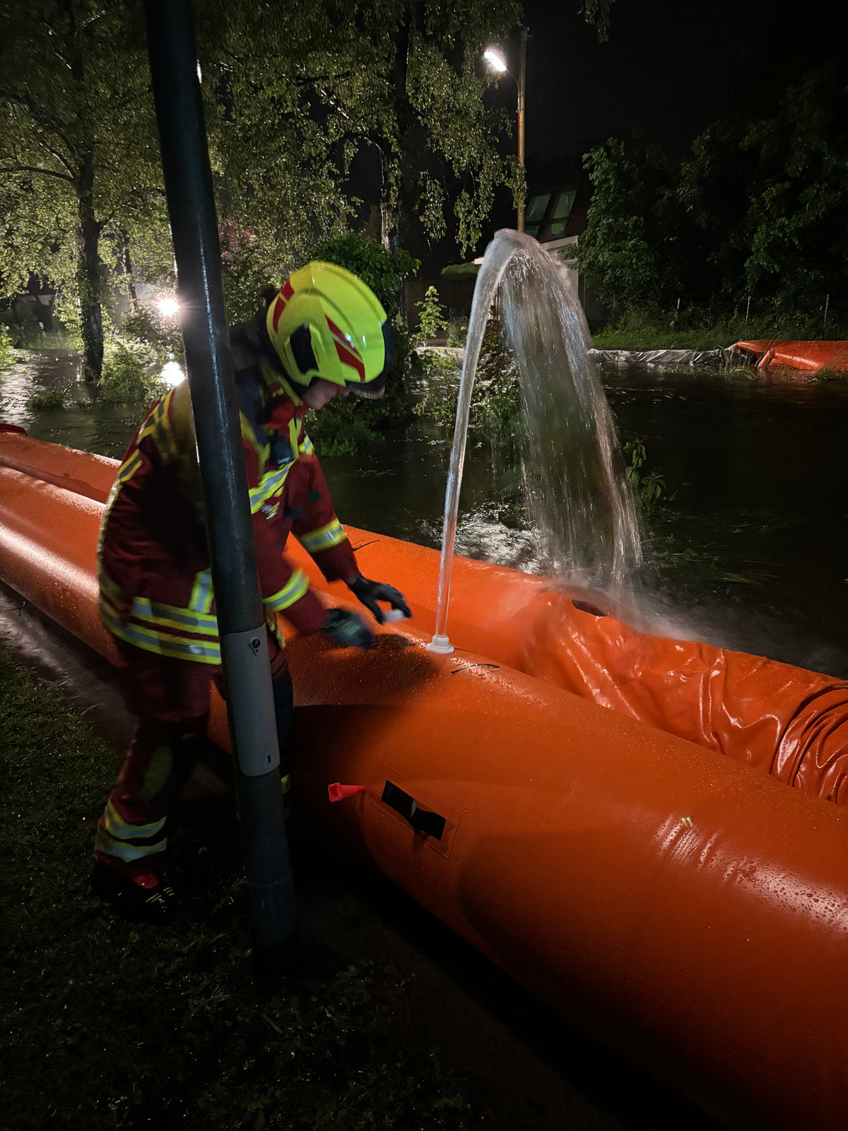Einsatzkraft der Feuerwehr an einem gefüllten Beaver Schlauchdamm bei Nacht