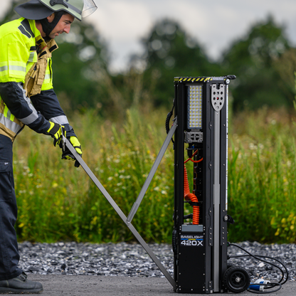 Einsatzkraft klappt den Standfuß des Baselight 420X aus, der Lichtmast steht auf seinen Transportrollen