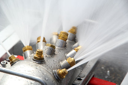 Messingdüsen des Löschigels im Betrieb, Wasserstrahlen treten in alle Richtungen aus
